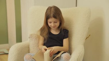 Genç bir kız lüks bir sandalyede rahatça oturur, bir kitaba dalmış olarak. Yırtık kotları ve günlük kıyafetleri rahat bir atmosfer olduğunu gösteriyor..