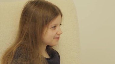 Gülümseyen kız bej bir koltukta oturuyor ve ekranın sağındaki bir şeye bakıyor, sağ tarafında fotokopi alanı olan..