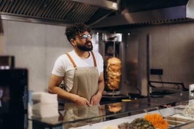Tezgahta duran aşçı canlı bir restoranda geleneksel shawarma ya da kebap hazırlıyor.