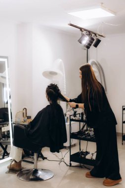 Modern bir kuaförde müşterinin saçını bakım ya da tedaviye hazırlayan kadın kuaför, güzellik hizmetleri sunuyor.