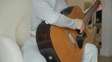 Bir kadın rahat ve rahat kıyafetlerle evde oturup gitar çalar. Yalnızlığının ve rahatlığının tadını çıkarıyor..