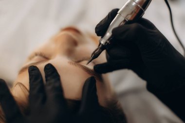 Kaşlarına kalıcı makyaj yaptıran bir kadın güzellik ve yüz hatlarını kozmetik dövmelerle geliştiriyor.