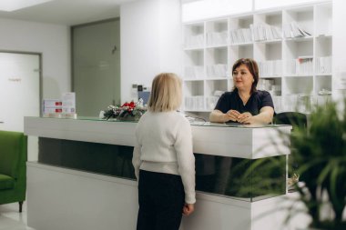 Modern bir sağlık kliniğinde dost canlısı bir resepsiyonistle hasta danışmanlığı, randevuların yönetimi ve idari görevler