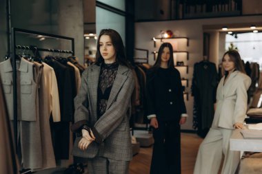 Modern bir perakende mağazasında şık kıyafetler deneyen genç kadınlar alışveriş deneyiminin tadını çıkarıyorlar.