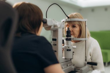 Kıdemli bir kadın sağlık kontrolü için sağlık kliniğindeki bir göz doktoru tarafından acilen muayene ediliyor.