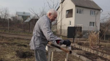 Arka bahçesinde çalışan usta tamirci restorasyon için boyamadan önce paslı bir boruyu süngerle özenle temizliyor.