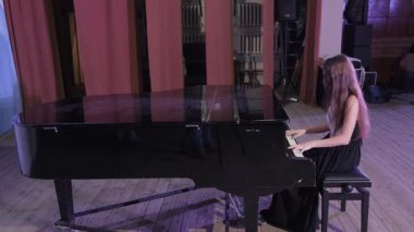 Profesyonel piyanist tiyatro salonundaki konser sırasında klasik müzik çalıyor. Müzikal tutku ve sanatsal ifade sergiliyor.