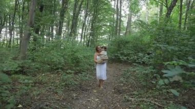 Bir anne küçük oğlunu taşırken ormanda yürür. İkisi de mutlular ve doğada birlikte vakit geçiriyorlar..