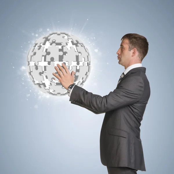 Businessman in suit hold and jigsaw puzzle sphere