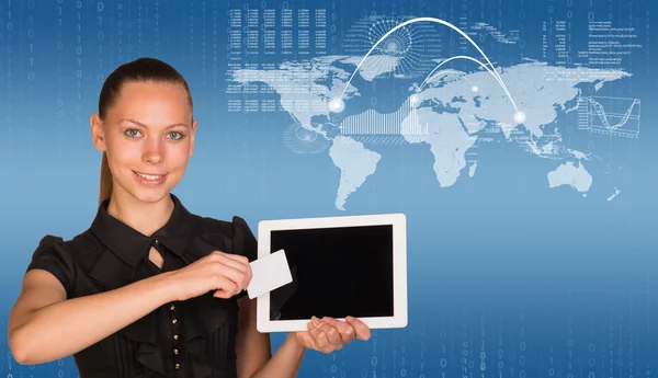 Beautiful businesswoman in dress holding tablet and white empty card near screen of tablet. World map, graphs, figures