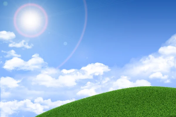 Green grassy hill. Background clouds and sun