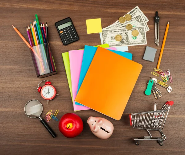 Shopping cart with office supplies and piggy bank