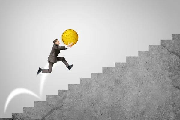 Businessman running up stairs holding big coin