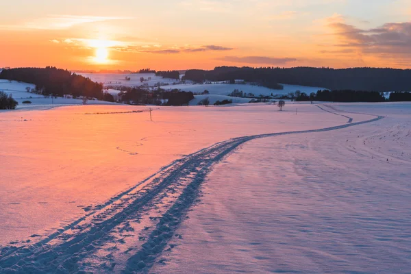 Scène met trail op sneeuw bij zonsondergang achtergrond — Stockfoto