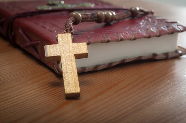 古い木製のキリスト教のロザリオの閉鎖ヴィンテージの赤い聖書に金の十字架と素朴な木製のテーブルの上 — ストック写真