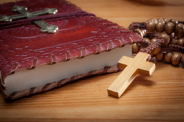圣经上有古老的红色圣经 上面有一个金十字架 在一张简陋的木桌上 用古老的木制基督教念珠做的衣服 — 图库照片