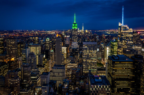 Aerial view of midtown Manhattan at night, the heart of a financial empire that dominates the business world, with every building vividly colored in shades of blue and green in NYC, state of New York, USA