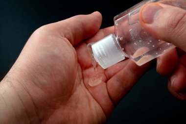 Bakterilerden, kişisel hijyenden ve grip koruma kavramından korunmak için koyu siyah arka planda izole edilmiş alkole dayalı el dezenfektanı jeli kullanın.