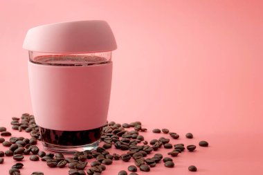 Enerji içecekleri, sabah rutini ve uyarıcı içecekler konsept bardak ve kauçuk kahve fincanları ile çevrili pembe arka planda izole edilmiş kahve çekirdekleri ile fotokopi alanı
