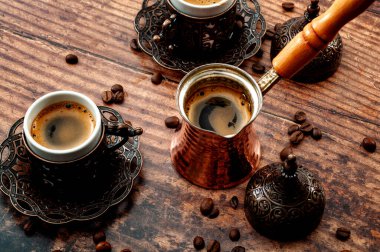 Geleneksel Türk kahve seti, ortadoğu kültürü ve metal bardak seti, ahşap saplı bakır çaydanlık ve ahşap arka planda izole kahve çekirdekleri içeren Arap geleneği teması