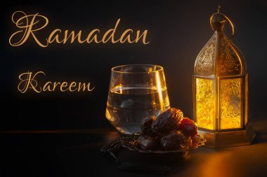 Ramazan Kareem, Müslüman dini geleneği, İslam 'da kutsal ay ve iftar konsepti temalı bir kase hurma, tespih, bir bardak su ve siyah arka planda Arapça fener.