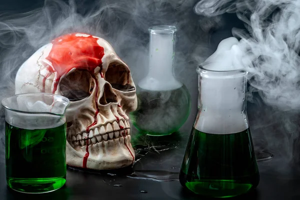 Biological warfare, chemical attack and genocide concept with a skull surrounded by chemistry flasks with smoke or mustard gas coming out of the green liquid