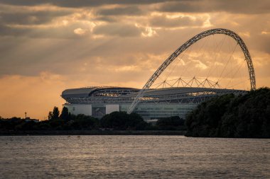 Londra, İngiltere - 6 Ekim 2016: Wembley Stadyumu günbatımında bir su kütlesinin karşısından. Wembley, İngiltere 'nin başkenti Londra' da bulunan bir futbol stadyumudur.