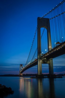 The bridge connecting Brooklyn to Staten Island named Verrazano bridge seen at dusk clipart