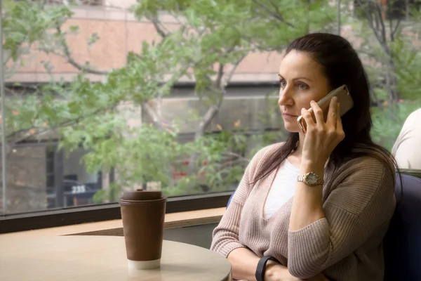 Woman in coffee shop has a very serious look on her face possibly because some relationship, financial or work issues