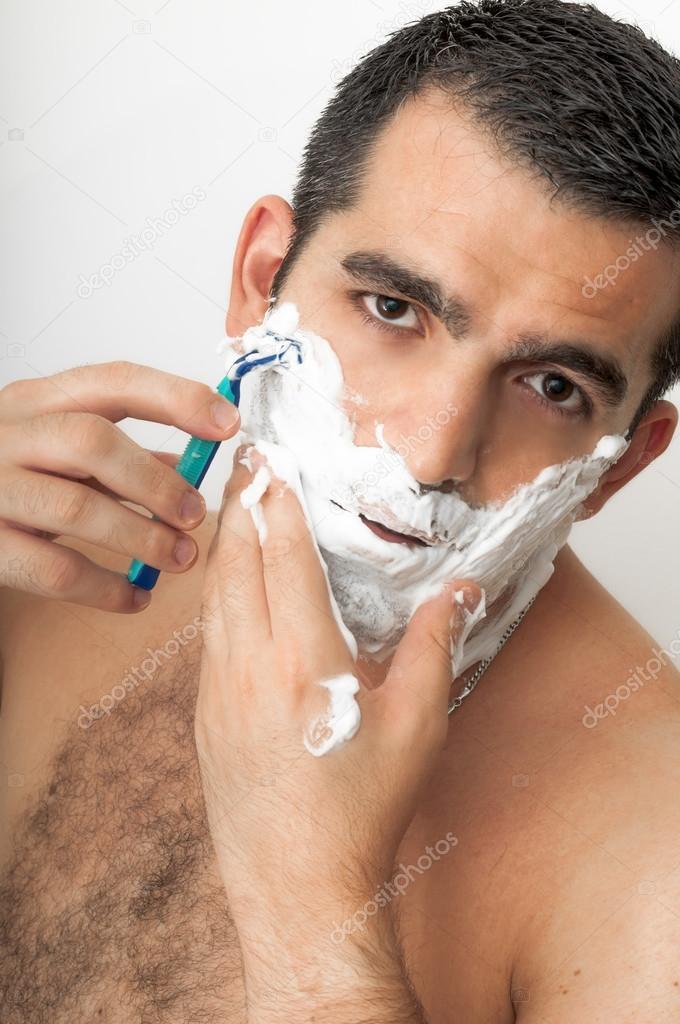 Italian or middle eastern looking man in his thirties shaving on white background