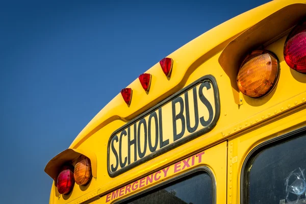 Крупный план школьного автобуса со спины со светофорами и видимым аварийным выходом — стоковое фото