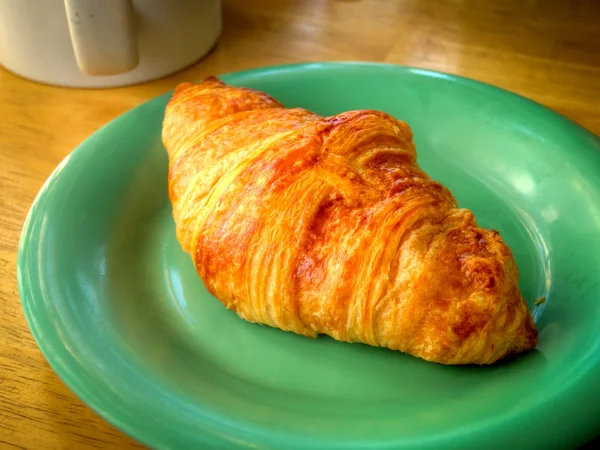 Ein armes Männerfrühstück, nur ein Croissant und eine Tasse Kaffee — Stockfoto