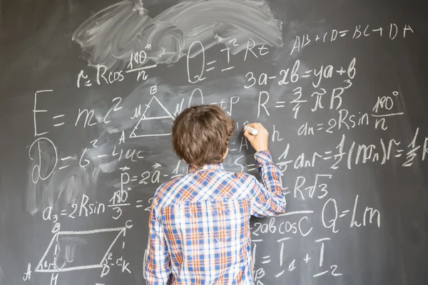 Boy writting on black board Stock Picture