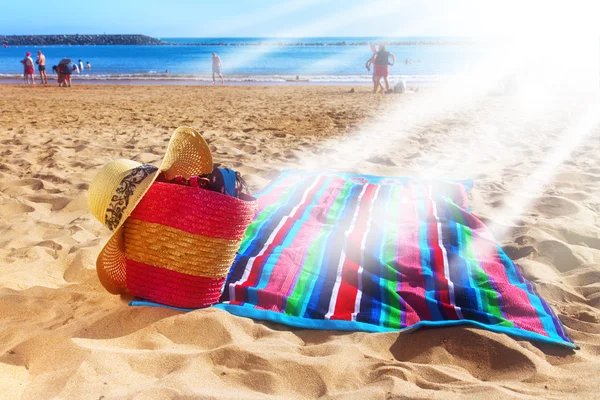 Handduk och korg på sandstrand — Stockfoto