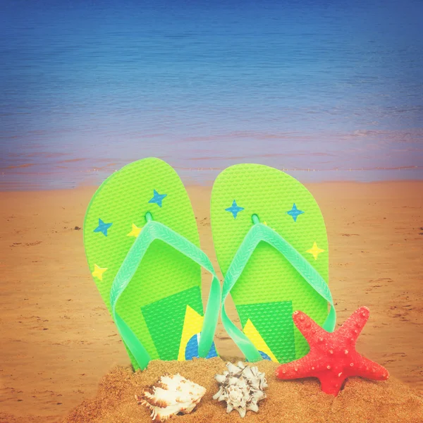 Green sandals and starfish in sand — Stock Photo, Image