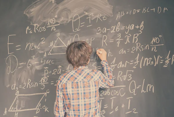 Boy writting on black board — Stok Foto