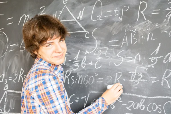 Boy writting on black board — Stok Foto