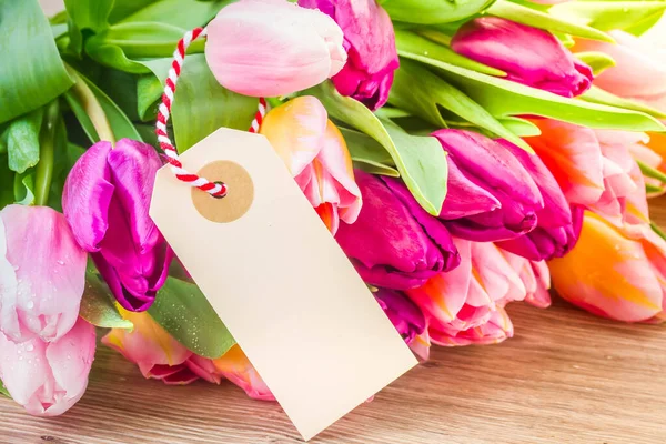 Pink and violet tulips with empty tag — Stock Photo, Image