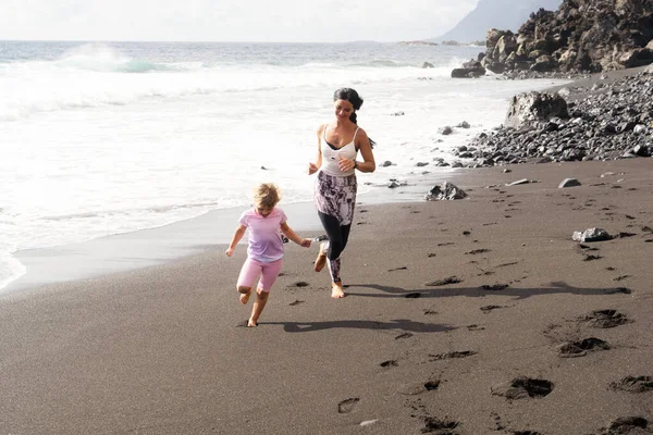Sağlıklı, mutlu bir aile annesi ve kızı deniz kenarında esneme egzersizleri yapıyor. — Stok fotoğraf