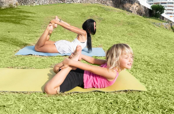 Saludable familia feliz mamá e hija haciendo ejercicios de estiramiento en la playa —  Fotos de Stock