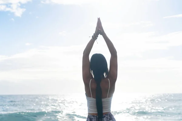 Mujer en ropa deportiva practicando yoga y meditando en la playa por la mañana — Foto de Stock