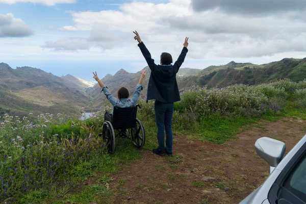Jeune homme et sa femme en fauteuil roulant voyageant ensemble en voiture dans les montagnes — Photo