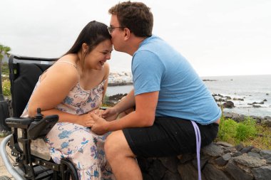 Disabled woman in wheelchair holding hand of her boyfriend while dating outdoors clipart
