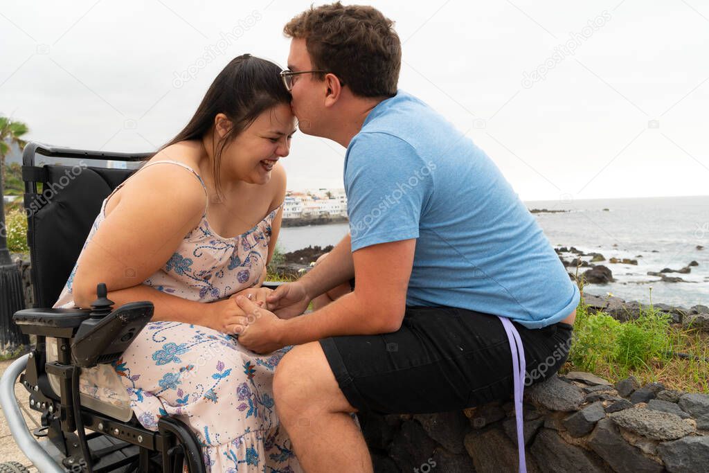 Disabled woman in wheelchair holding hand of her boyfriend while dating outdoors