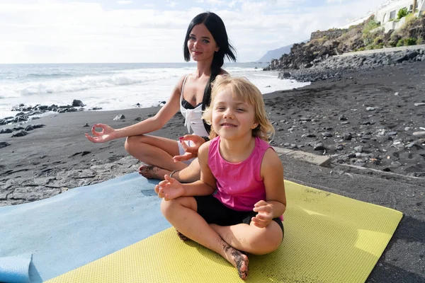 Saludable familia feliz mamá e hija haciendo ejercicios de estiramiento en la playa — Foto de Stock