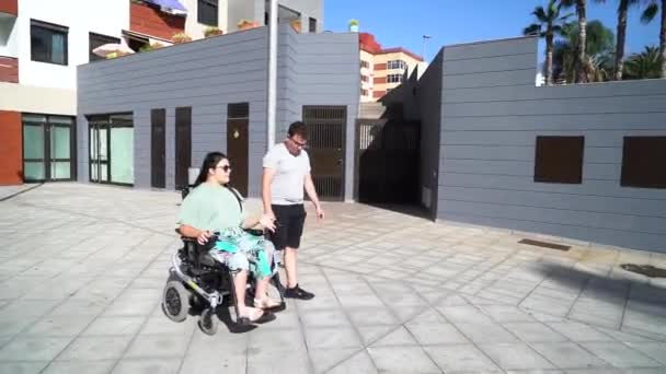 Jonge gehandicapte vrouw in rolstoel dating met haar vriendje buiten — Stockvideo