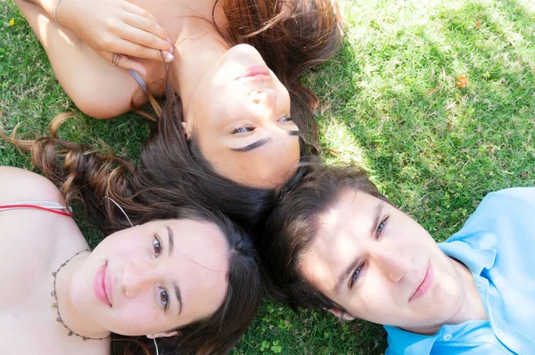 행복 한 십 대 청소년들 이 목초지의 푸른 풀 위에서 휴식을 취하며 평화의 표시를 하는 모습 — 스톡 사진