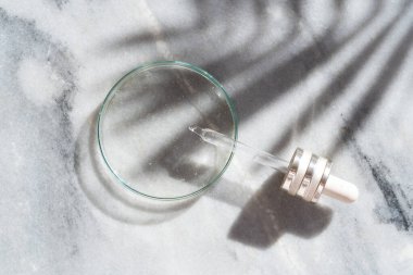 Cilt bakımı için şeffaf serum içeren cam petri kabı.