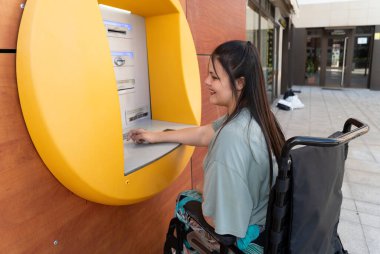 ATM ile tekerlekli sandalyedeki engelli genç kadın.