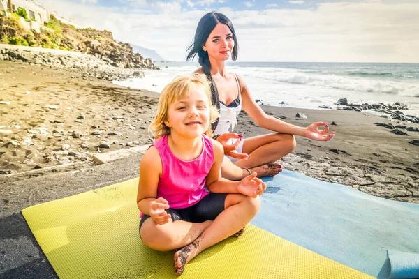 Healthy happy family mom and daughter doing stretching exercises on seaside — Stock Photo, Image